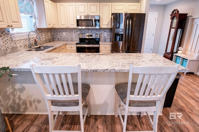 kitchen featuring a sink, appliances with stainless steel finishes, light stone counters, and light wood finished floors