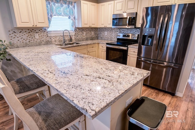 kitchen with light wood-style flooring, a breakfast bar, a sink, and stainless steel appliances