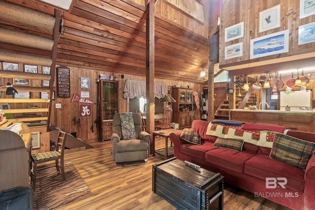 living room with beamed ceiling, hardwood / wood-style flooring, high vaulted ceiling, and wood walls