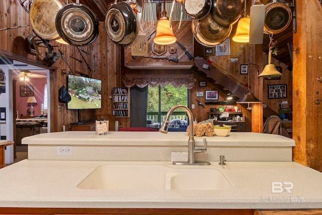 kitchen featuring ceiling fan, wood walls, and sink