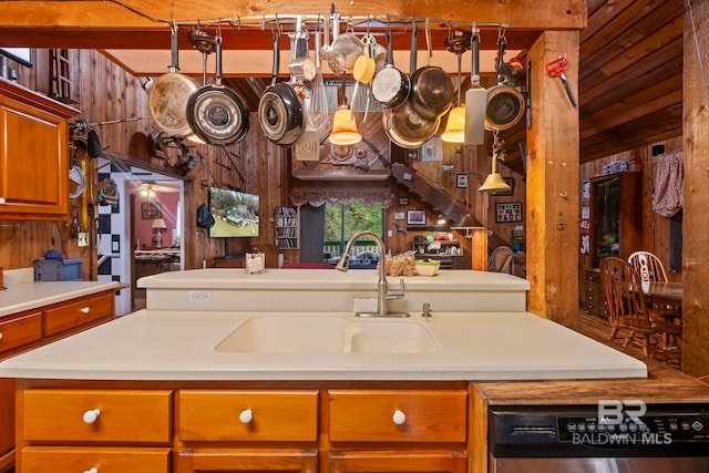 kitchen featuring sink, stainless steel dishwasher, ceiling fan, and wood walls