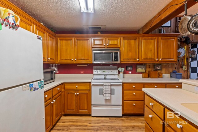 kitchen with a textured ceiling, white appliances, and light wood-type flooring