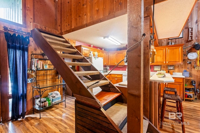 stairway with a textured ceiling, hardwood / wood-style flooring, and wood walls