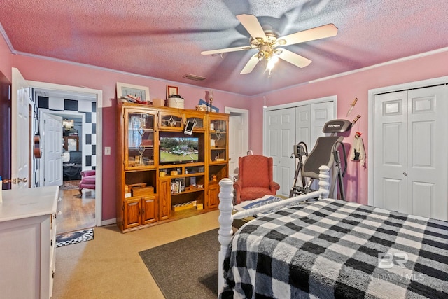 bedroom with multiple closets, ceiling fan, and a textured ceiling