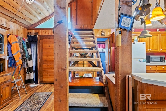 staircase featuring hardwood / wood-style floors, wood walls, wood ceiling, and vaulted ceiling