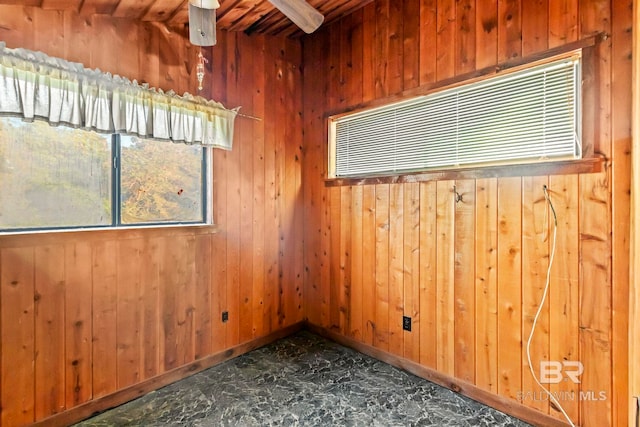 empty room featuring vaulted ceiling with beams, wooden walls, and ceiling fan