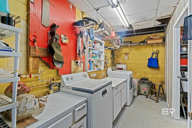 washroom featuring a workshop area, washer and clothes dryer, and cabinets