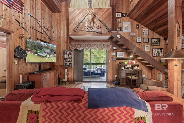 living room with hardwood / wood-style floors, high vaulted ceiling, and wooden walls