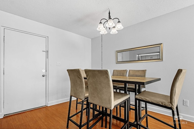 dining space with a chandelier, a textured ceiling, and hardwood / wood-style flooring