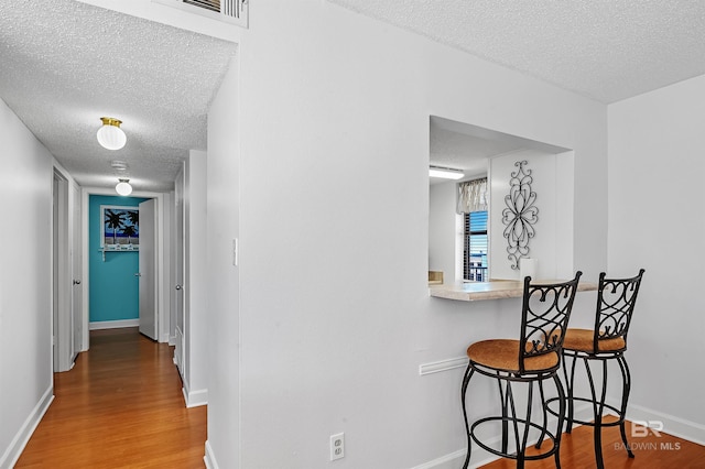 hall featuring a textured ceiling and hardwood / wood-style flooring