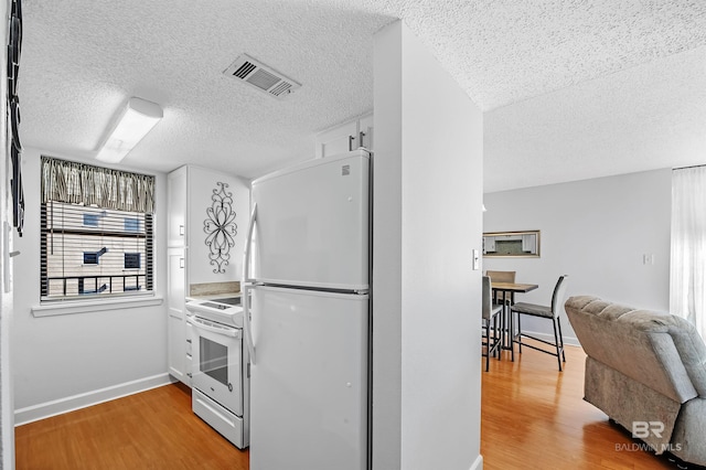 kitchen with white refrigerator, stove, a textured ceiling, and light hardwood / wood-style flooring