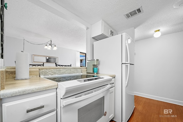 kitchen with white cabinetry, dark wood-type flooring, an inviting chandelier, white range with electric stovetop, and a textured ceiling