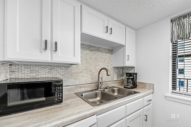 kitchen featuring backsplash, white cabinetry, sink, and a textured ceiling