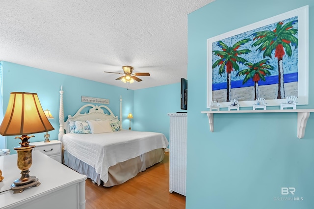 bedroom featuring ceiling fan, a textured ceiling, and light wood-type flooring