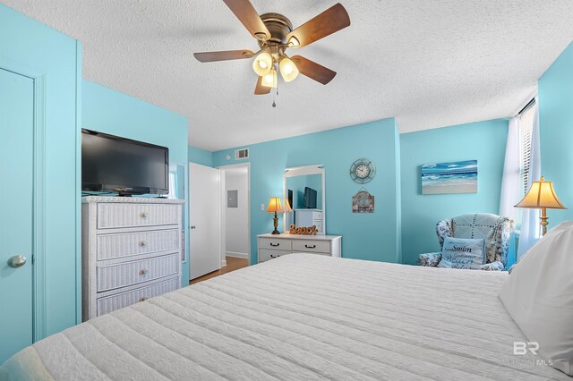 bedroom featuring wood-type flooring, a textured ceiling, and ceiling fan