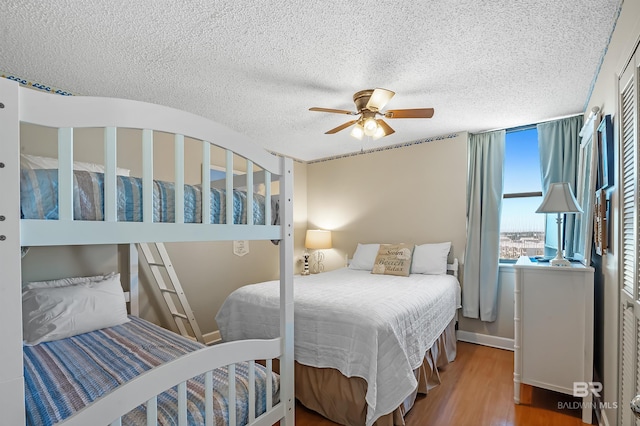 bedroom with ceiling fan, hardwood / wood-style floors, and a textured ceiling