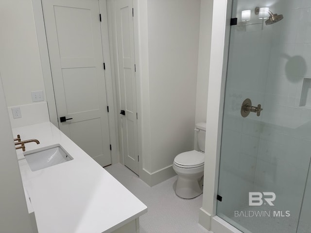 bathroom featuring toilet, a shower with shower door, vanity, and tile patterned floors