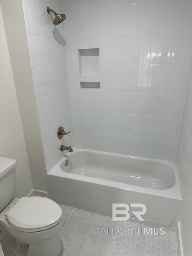 bathroom featuring toilet, tiled shower / bath combo, and tile patterned flooring