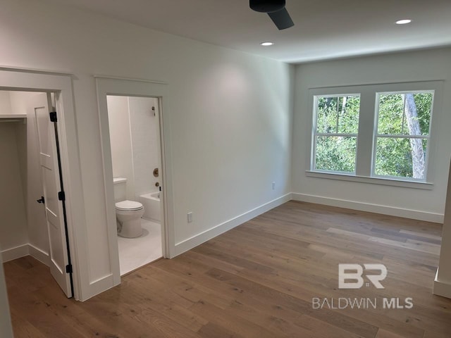 interior space featuring light hardwood / wood-style flooring, ensuite bath, and ceiling fan