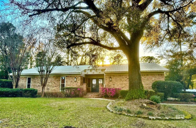 ranch-style house with metal roof, brick siding, and a front yard