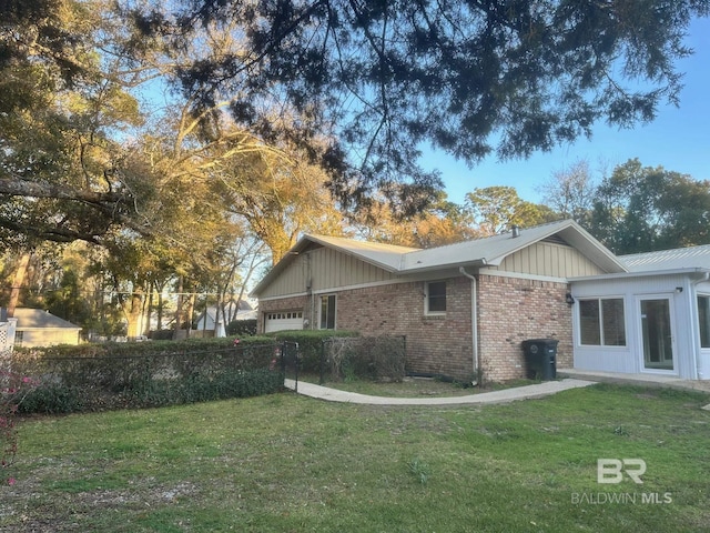 view of property exterior with fence, a yard, brick siding, and a garage