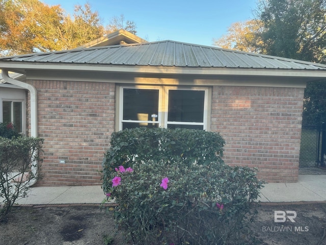 exterior space with brick siding and metal roof