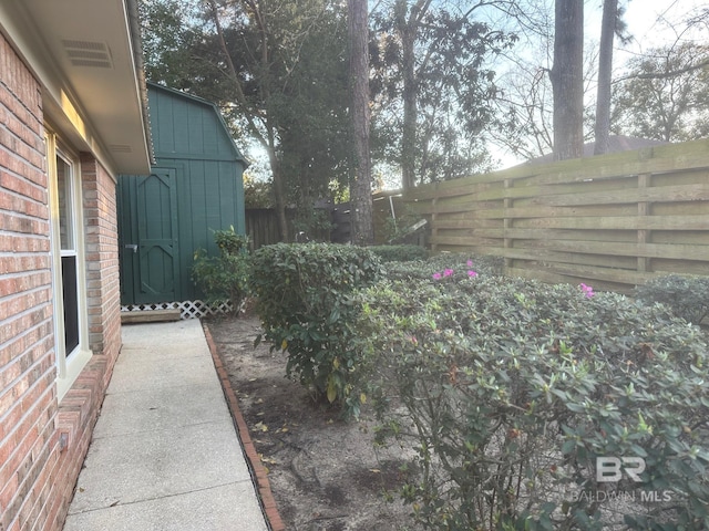 view of yard featuring an outbuilding, a storage unit, and fence