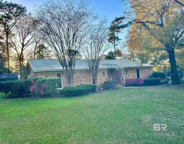 exterior space with brick siding and a yard