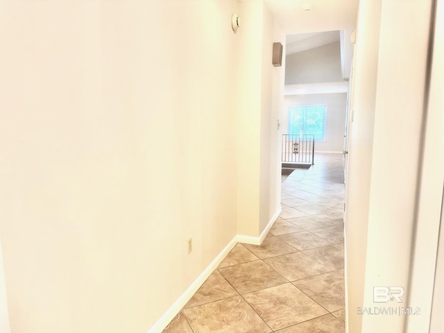 hallway featuring baseboards and light tile patterned flooring