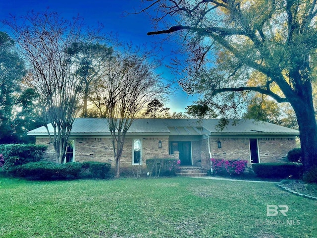 single story home with a front lawn, brick siding, and metal roof