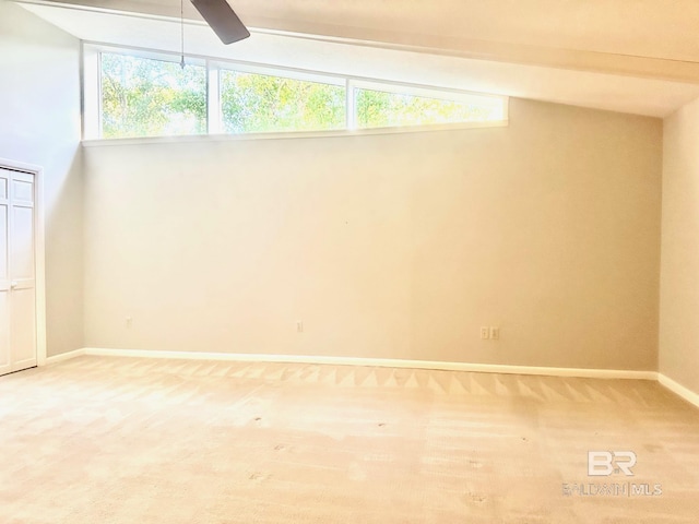 carpeted empty room with plenty of natural light, vaulted ceiling with beams, baseboards, and a ceiling fan