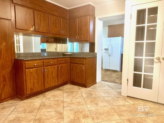 kitchen featuring light tile patterned floors, brown cabinets, white fridge with ice dispenser, and crown molding