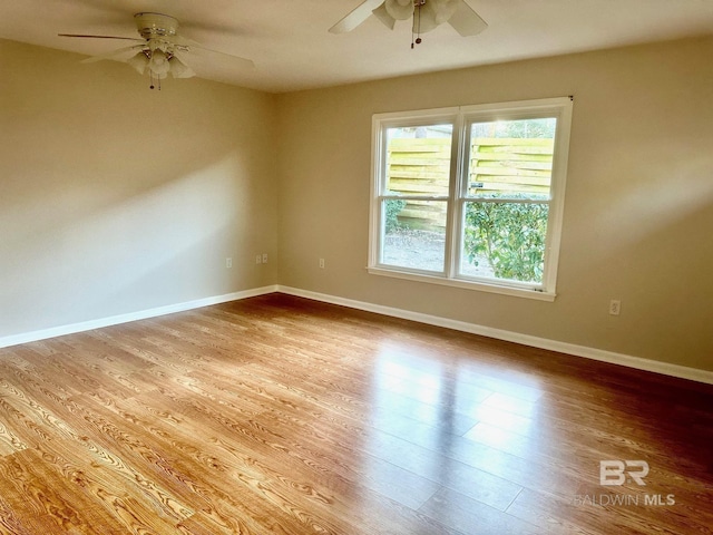 spare room featuring wood finished floors, a ceiling fan, and baseboards