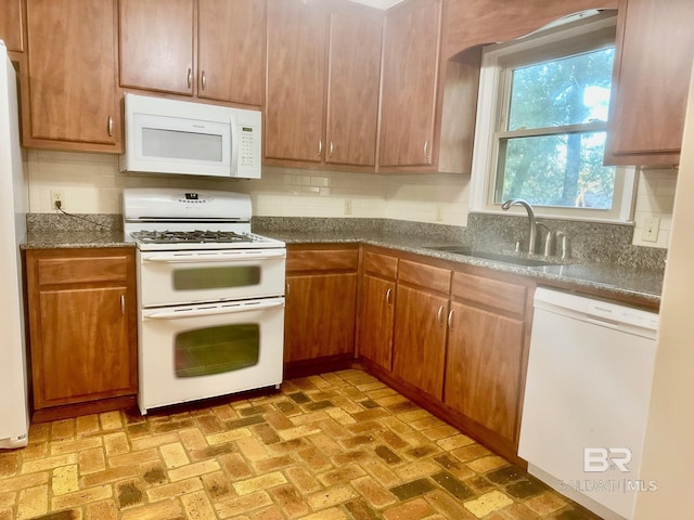 kitchen with white appliances, brick floor, tasteful backsplash, and a sink