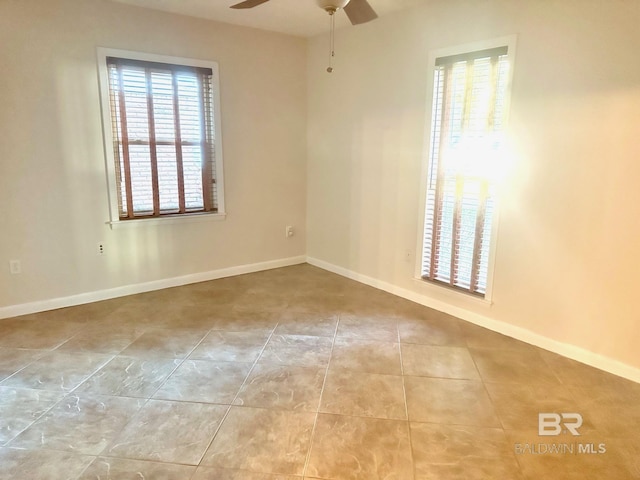 tiled spare room featuring baseboards and ceiling fan