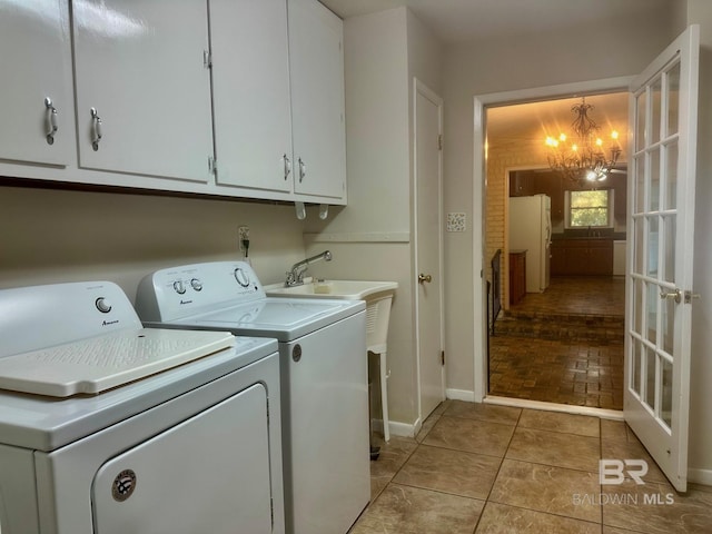 washroom featuring washer and clothes dryer, light tile patterned floors, an inviting chandelier, cabinet space, and a sink