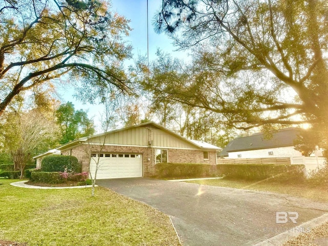 ranch-style home with aphalt driveway, brick siding, a garage, and a front lawn