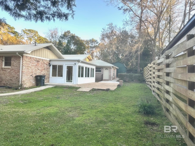 rear view of house featuring a patio, a lawn, and brick siding