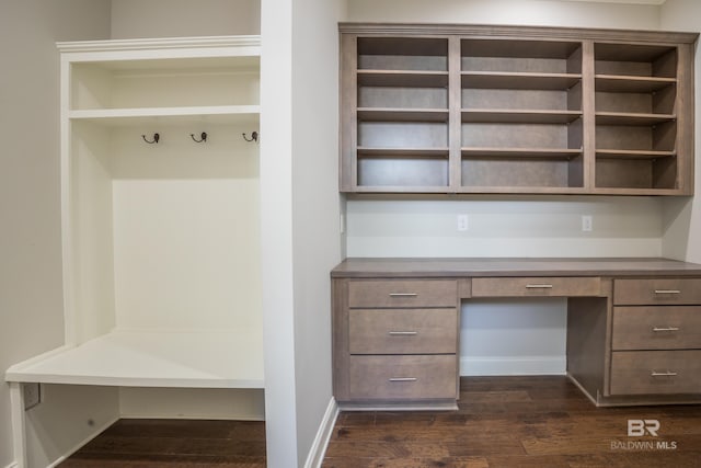 mudroom with built in desk and dark wood-type flooring