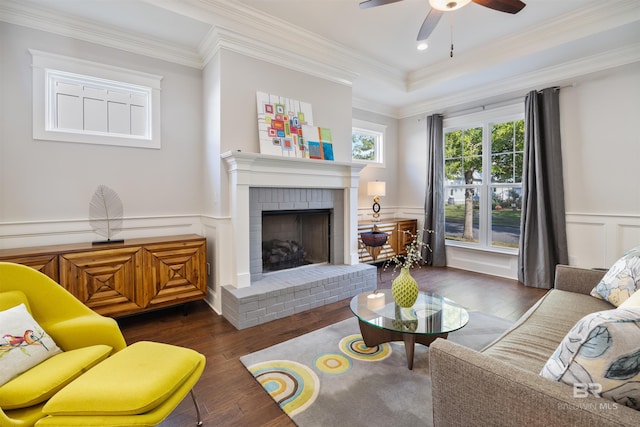 living room with dark wood-type flooring, a brick fireplace, ornamental molding, and ceiling fan