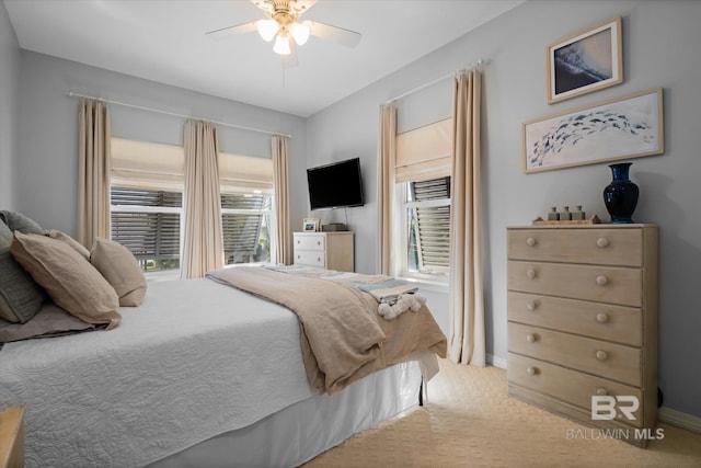 bedroom with ceiling fan, light carpet, and multiple windows