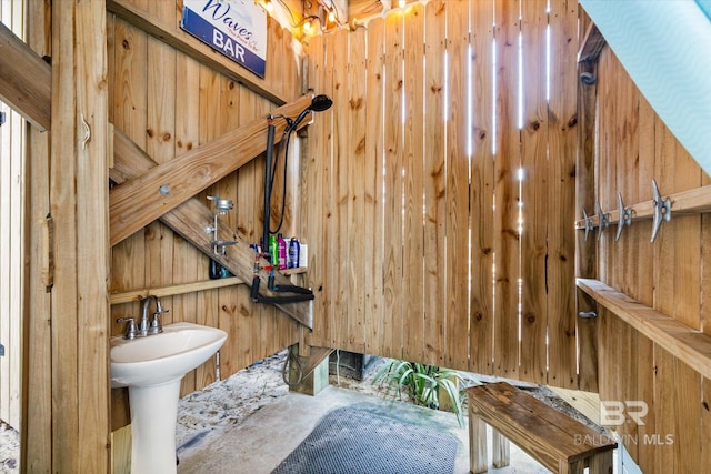 bathroom featuring concrete floors and wooden walls