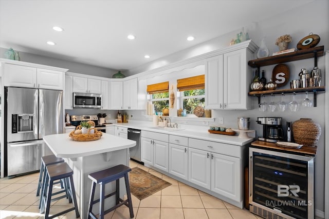 kitchen with white cabinets, sink, appliances with stainless steel finishes, a breakfast bar area, and beverage cooler