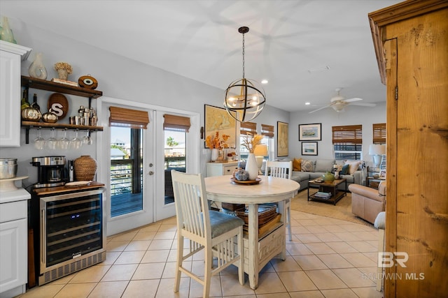 dining room featuring ceiling fan with notable chandelier, light tile patterned flooring, beverage cooler, and french doors