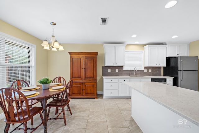kitchen with sink, appliances with stainless steel finishes, pendant lighting, light stone countertops, and white cabinets