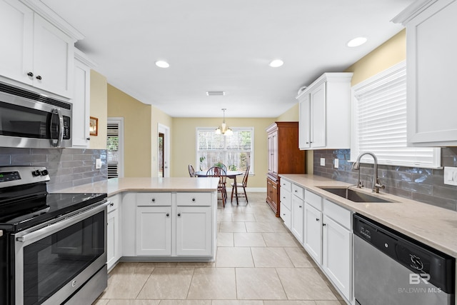 kitchen with decorative light fixtures, sink, white cabinets, kitchen peninsula, and stainless steel appliances