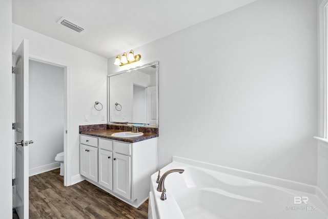 bathroom featuring vanity, wood-type flooring, a bathtub, and toilet