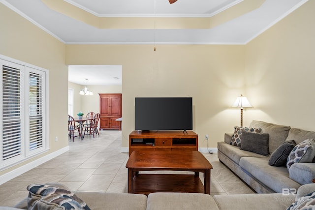 tiled living room with crown molding, ceiling fan with notable chandelier, and a tray ceiling