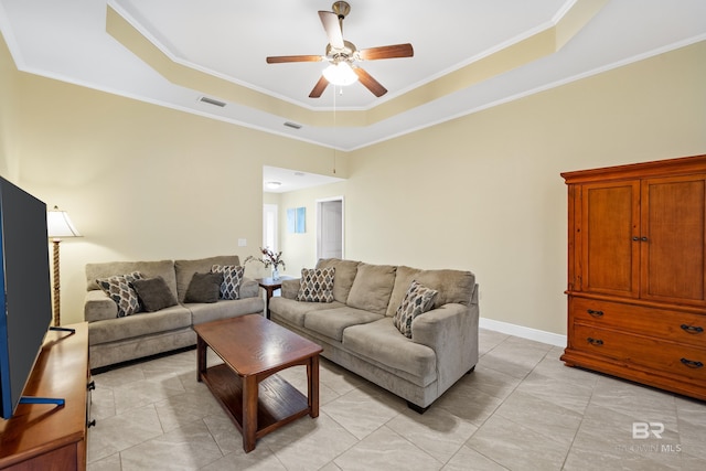 living room with crown molding, light tile patterned floors, ceiling fan, and a tray ceiling