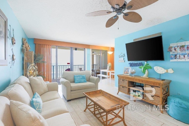 living room with ceiling fan, a textured ceiling, and light hardwood / wood-style floors